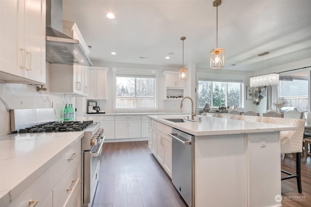 kitchen with appliances with stainless steel finishes, decorative light fixtures, a kitchen island with sink, and white cabinets