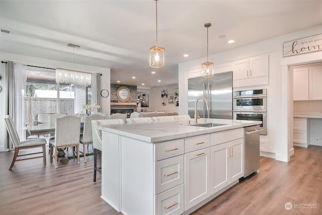 kitchen featuring pendant lighting, light stone countertops, white cabinets, and appliances with stainless steel finishes