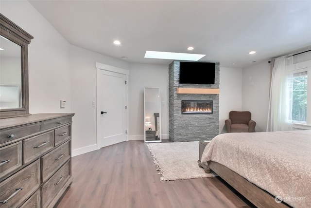 bedroom featuring a skylight, a fireplace, and dark hardwood / wood-style flooring