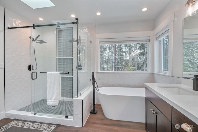 bathroom with vanity, plus walk in shower, hardwood / wood-style floors, and a skylight