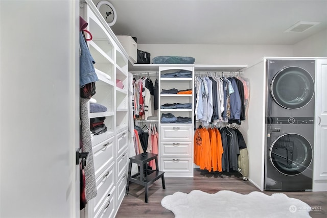 walk in closet featuring stacked washer and dryer and dark hardwood / wood-style floors