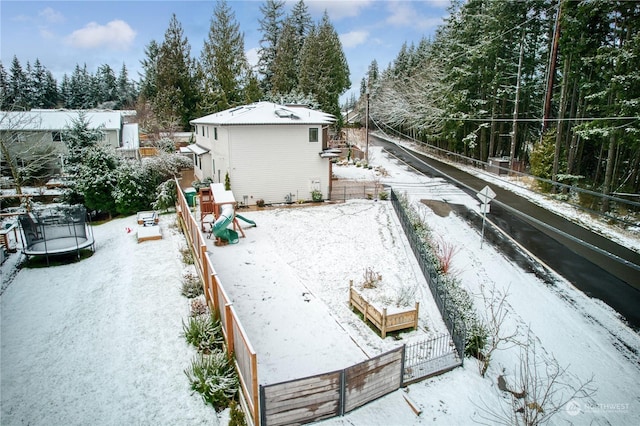 yard layered in snow with a playground and a trampoline