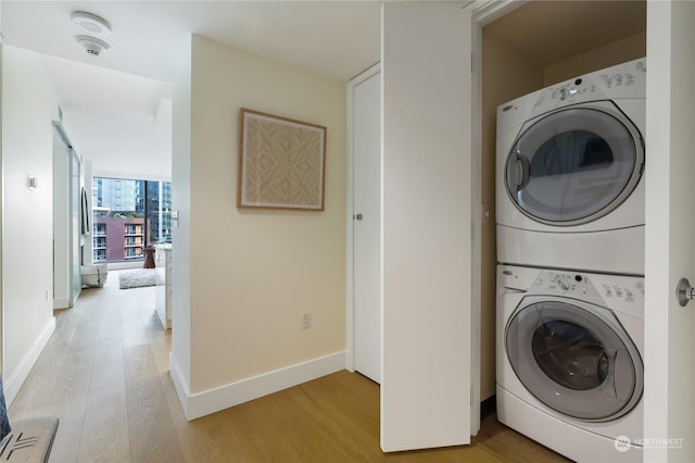 clothes washing area featuring hardwood / wood-style flooring and stacked washer and clothes dryer