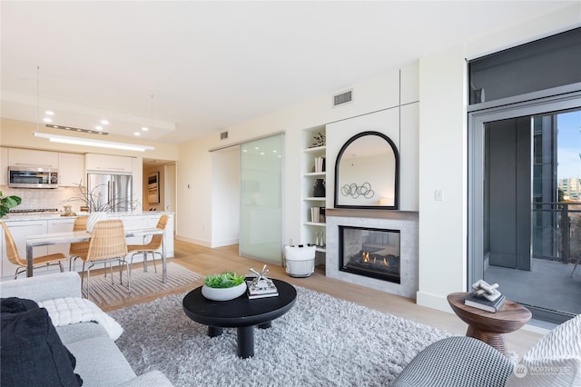 living room featuring built in features and light wood-type flooring