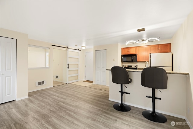 kitchen featuring stainless steel range with electric stovetop, light stone counters, fridge, light hardwood / wood-style flooring, and a barn door