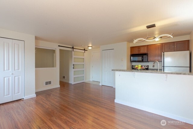300 10th Ave Unit A203, Seattle, WA 98122 - kitchen with black microwave, freestanding refrigerator, a barn door, a breakfast bar area, and range