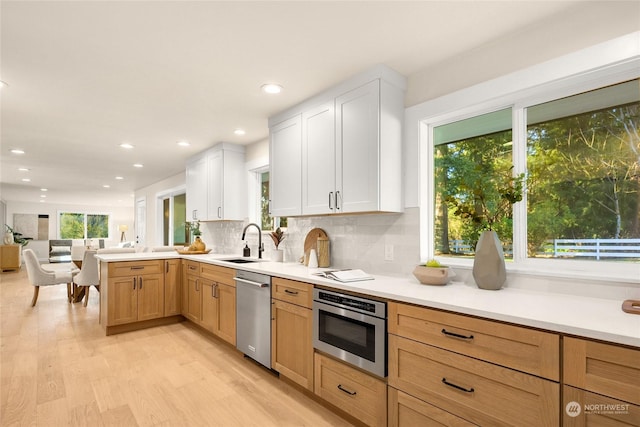 kitchen featuring sink, dishwasher, kitchen peninsula, oven, and white cabinets