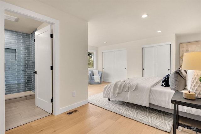 bedroom with connected bathroom, light hardwood / wood-style flooring, and multiple closets