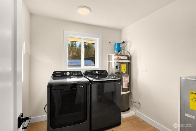 laundry room featuring strapped water heater, light hardwood / wood-style flooring, and washing machine and dryer