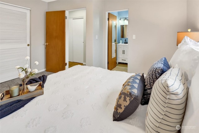 carpeted bedroom featuring a closet, sink, and ensuite bath