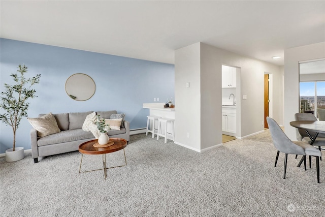 living room with light colored carpet, baseboard heating, and sink