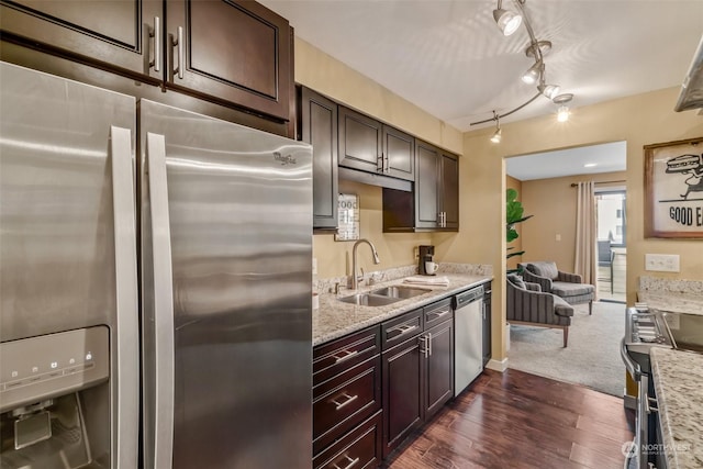 kitchen with sink, dark wood-type flooring, light stone counters, stainless steel appliances, and dark brown cabinets