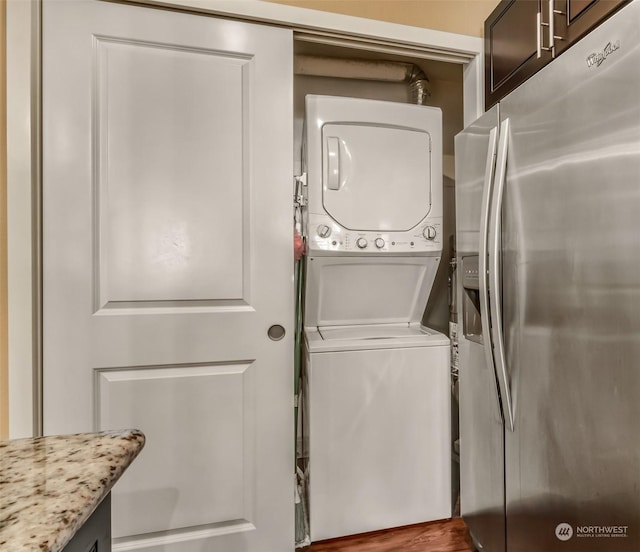 laundry room with wood-type flooring and stacked washer and clothes dryer