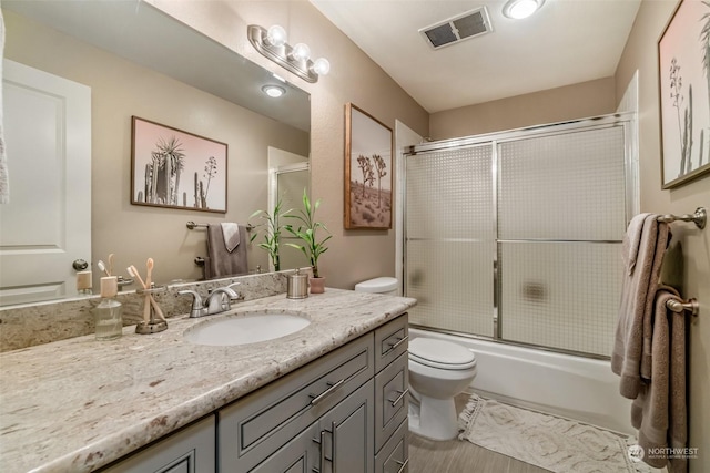 full bathroom featuring vanity, enclosed tub / shower combo, and toilet