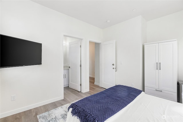 bedroom with ensuite bath and light hardwood / wood-style flooring