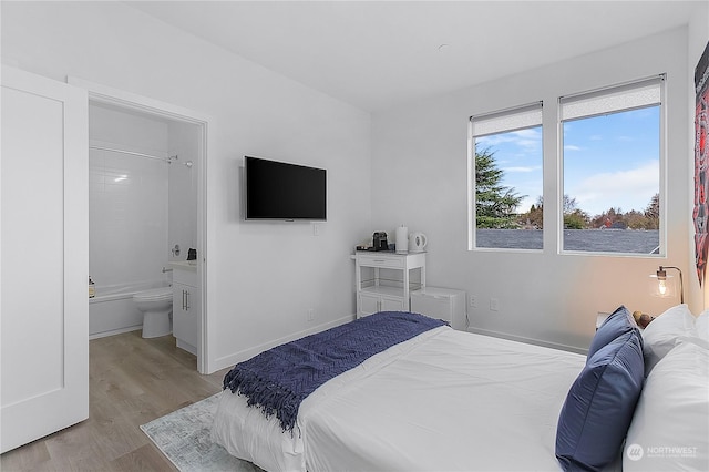 bedroom with connected bathroom and light hardwood / wood-style floors