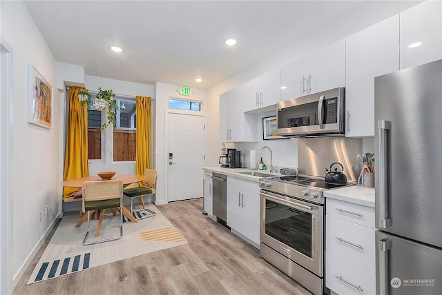 kitchen featuring appliances with stainless steel finishes, sink, white cabinets, and light wood-type flooring