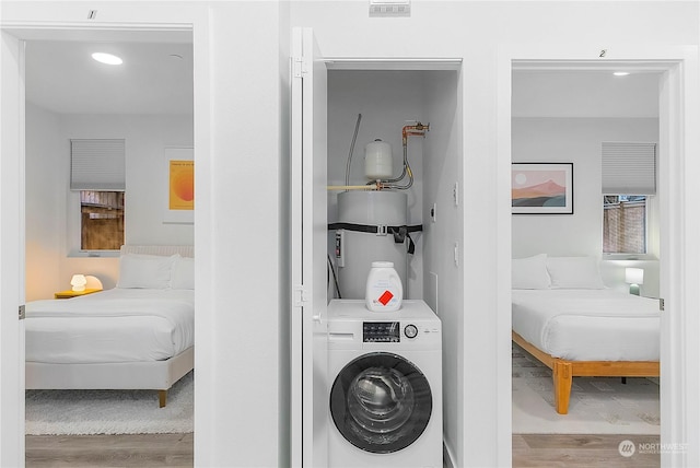 laundry area featuring washer / clothes dryer, light wood-type flooring, and strapped water heater