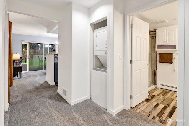 corridor featuring light colored carpet, stacked washer / dryer, and a baseboard radiator