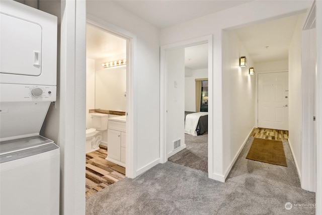 bathroom featuring toilet, stacked washing maching and dryer, and vanity