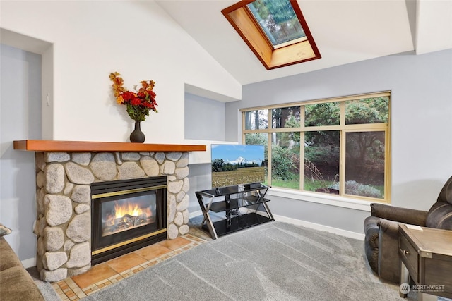 sitting room with vaulted ceiling with skylight and a stone fireplace