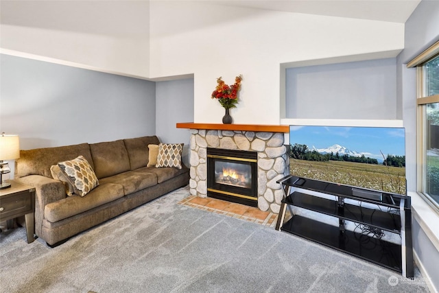 living room featuring vaulted ceiling, light colored carpet, plenty of natural light, and a stone fireplace