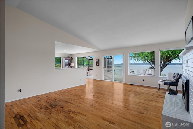 4030 Kamilche Point Rd, Shelton, WA 98584 - unfurnished living room with vaulted ceiling, wood finished floors, and a water view