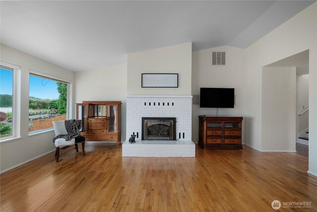 4030 Kamilche Point Rd, Shelton, WA 98584 - living area featuring light wood finished floors, a brick fireplace, stairway, lofted ceiling, and baseboards