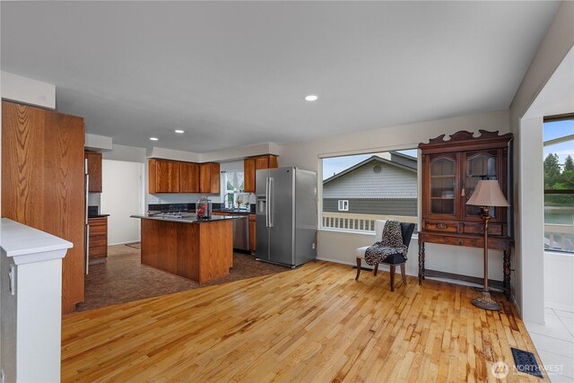 4030 Kamilche Point Rd, Shelton, WA 98584 - kitchen featuring appliances with stainless steel finishes, light wood finished floors, brown cabinetry, dark countertops, and a center island