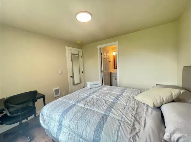 bedroom with hardwood / wood-style flooring and ensuite bath