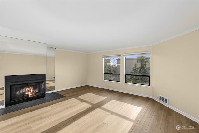 unfurnished living room featuring crown molding and hardwood / wood-style floors