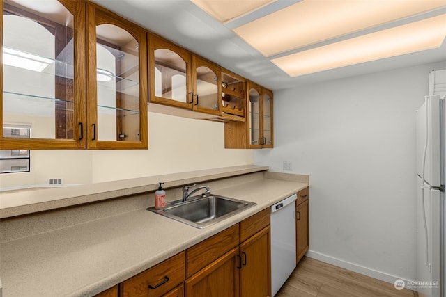 kitchen with sink, white appliances, and light hardwood / wood-style floors