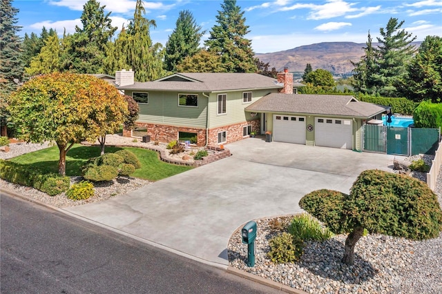 view of front of home with brick siding, a chimney, concrete driveway, an attached garage, and a mountain view