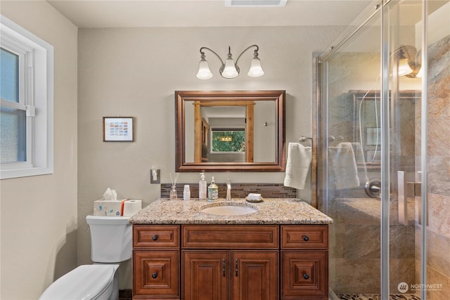 bathroom featuring toilet, a shower with shower door, and vanity