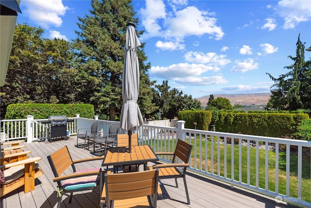 wooden deck with a mountain view, a yard, and area for grilling