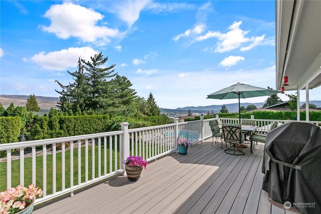 wooden deck featuring a mountain view, a grill, and a lawn