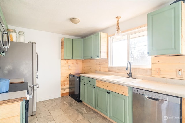 kitchen with appliances with stainless steel finishes, wooden walls, sink, hanging light fixtures, and green cabinetry