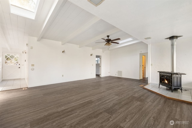 unfurnished living room with ceiling fan, beam ceiling, hardwood / wood-style floors, and a wood stove