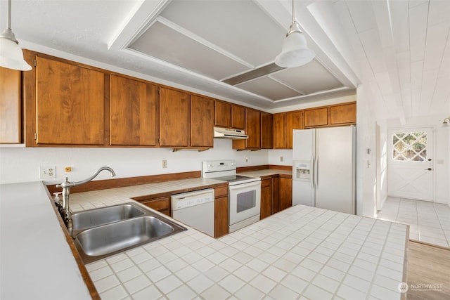 kitchen featuring tile counters, white appliances, decorative light fixtures, and sink