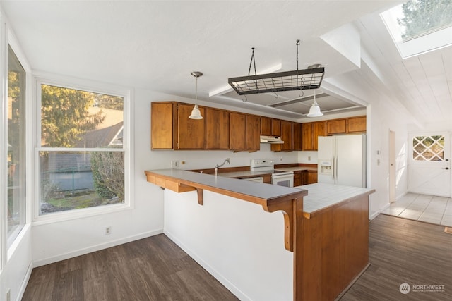 kitchen featuring white appliances, decorative light fixtures, kitchen peninsula, and a skylight