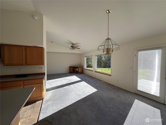 unfurnished living room featuring dark carpet, vaulted ceiling, and ceiling fan with notable chandelier