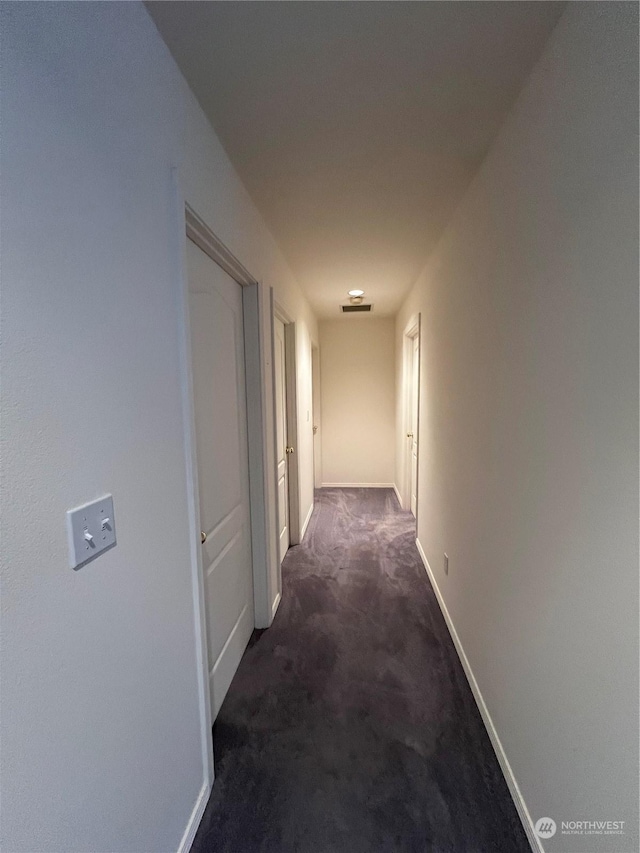 hall with dark colored carpet