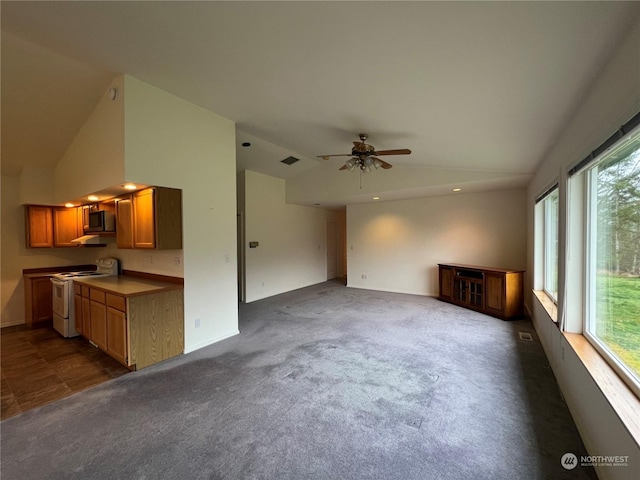 unfurnished living room with lofted ceiling, a wealth of natural light, and dark colored carpet