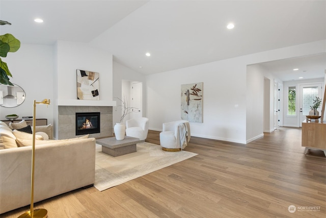 living room featuring wood-type flooring, vaulted ceiling, and a fireplace