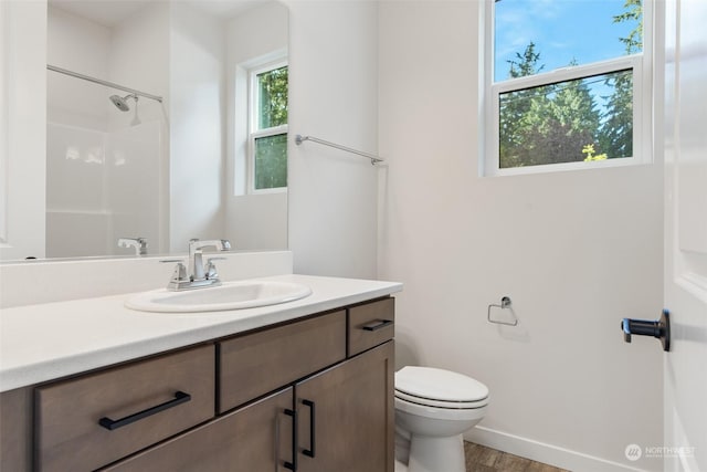 bathroom featuring toilet, hardwood / wood-style flooring, a shower, and vanity