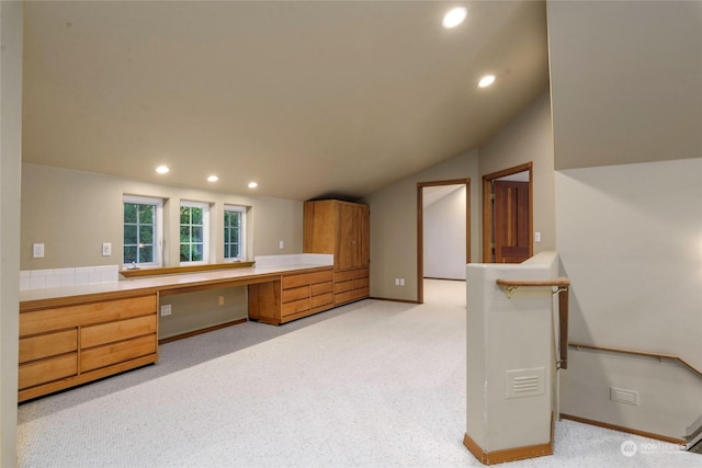 interior space with light carpet, lofted ceiling, and built in desk