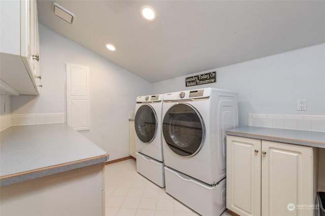 washroom with light tile patterned floors, cabinets, and washer and clothes dryer