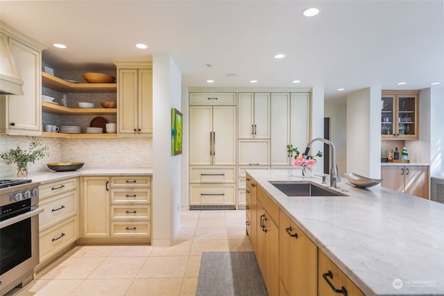 kitchen featuring sink, tasteful backsplash, light tile patterned floors, light stone countertops, and stove