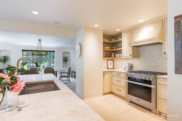 kitchen featuring light tile patterned floors, sink, gas stove, custom range hood, and cream cabinetry