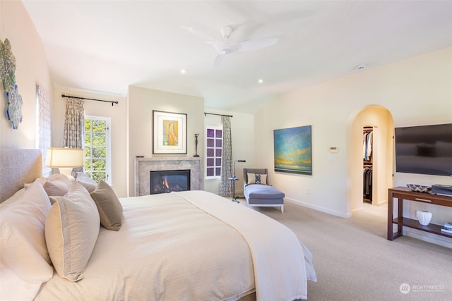 carpeted bedroom featuring vaulted ceiling, a walk in closet, and ceiling fan